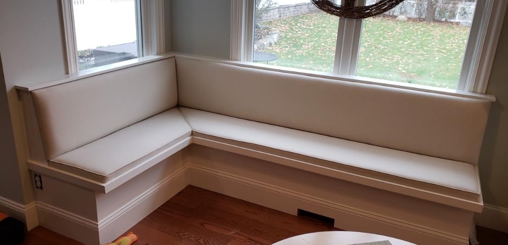 Custom upholstered white banquette seating in bay window nook by Designs In Blinds & Drapes